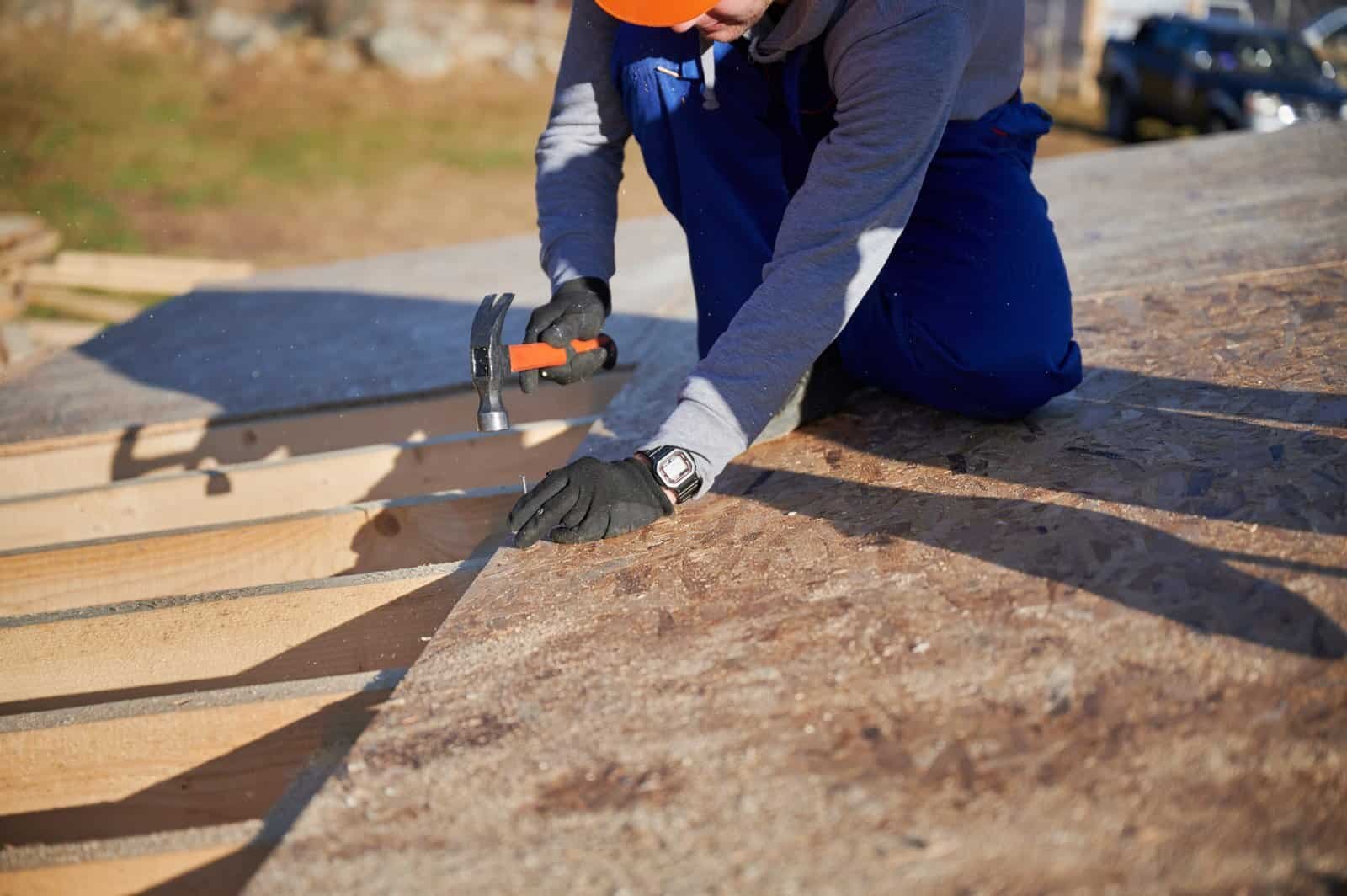 Worker installing roofing shingles on a residential roof in Redlands, CA.