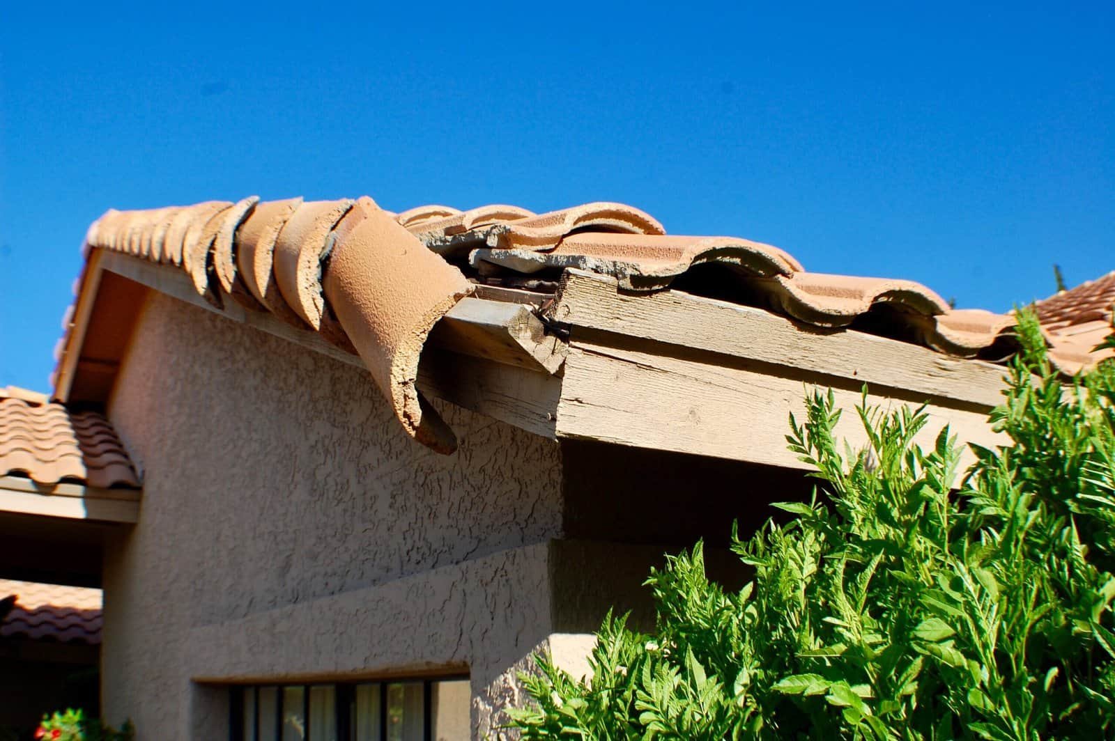 Damaged roof edge with broken tiles and wooden soffit in Redlands, California.
